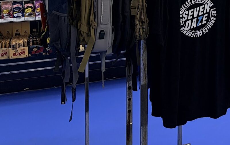 Backpacks and Seven Daze shop tees on the floor rack.