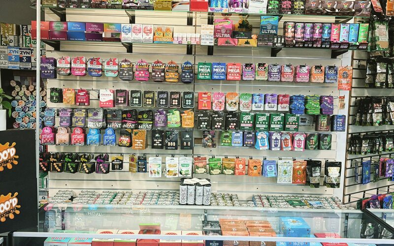 The lit glass case of hand pipes by the register.