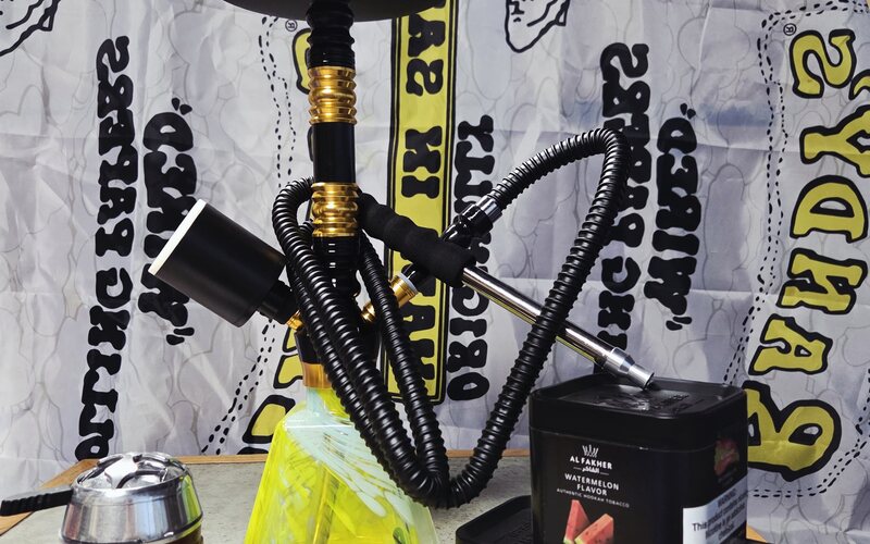 A black and gold hookah with an Al Fakher tin on the counter.