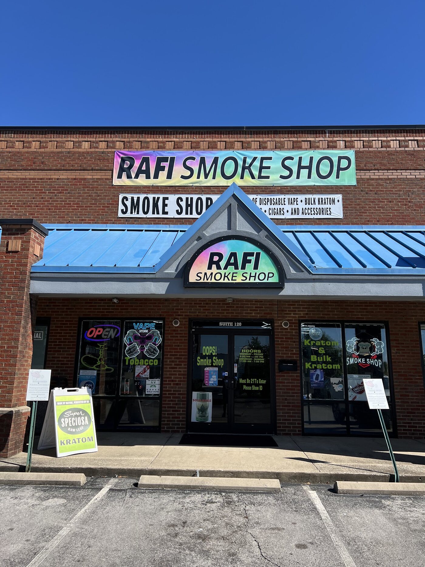 The storefront of Rafi Smoke Shop: red brick with a blue awning, a rainbow RAFI SMOKE SHOP banner, and neon signs in the windows.